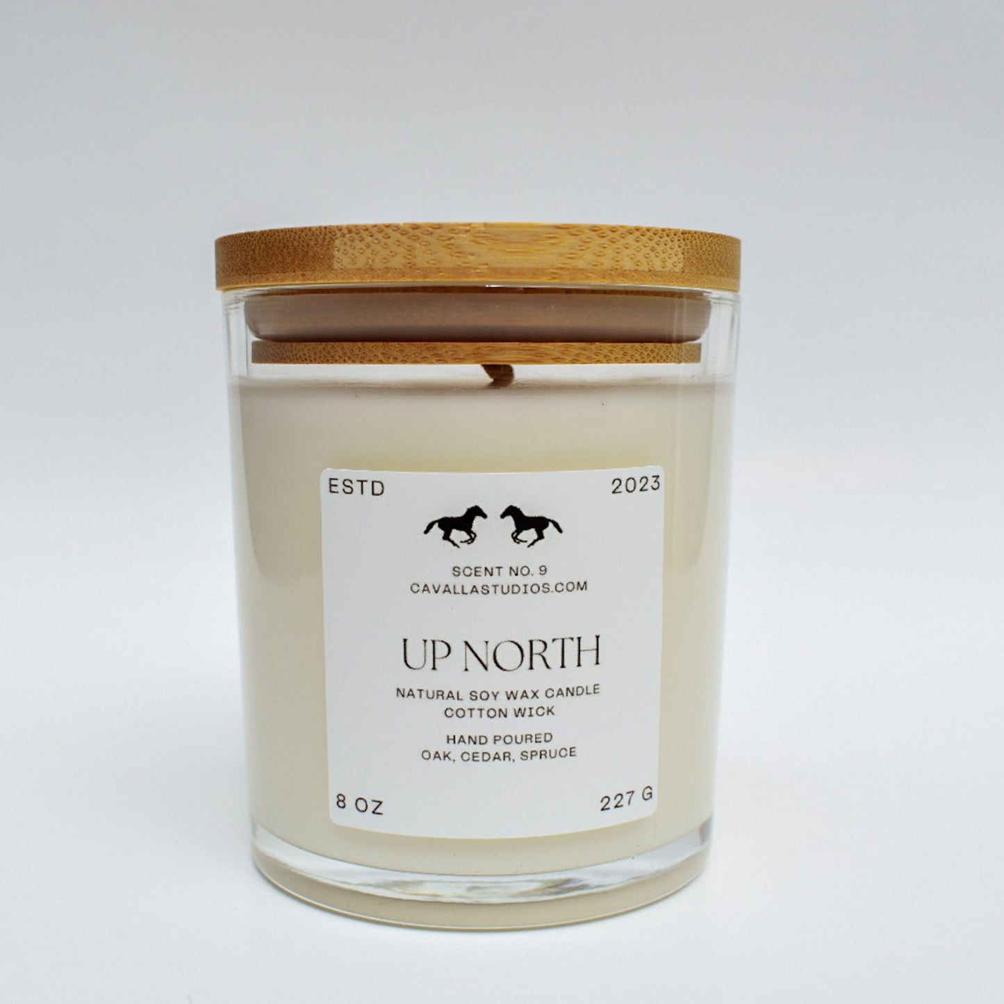 Classic white candle in a clear glass vessel covered by a bamboo lid. The glass features the 'Cavalla Studios' logo and the candle is labeled with the scent name 'Up North.'